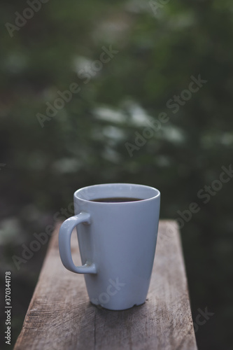 Black coffee mug on natural blurred background Dark tone style