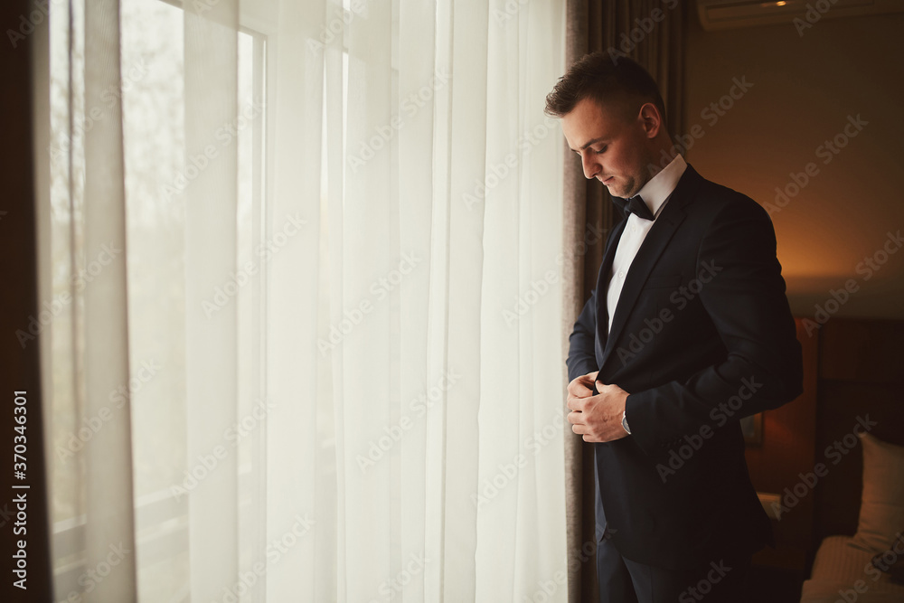 Morning of the groom before the wedding. Groom morning preparation. Young and handsome groom getting dressed in a wedding suit. Morning of the groom before the wedding. Groom morning preparation. Young and handsome groom getting dressed in a wedding suit.