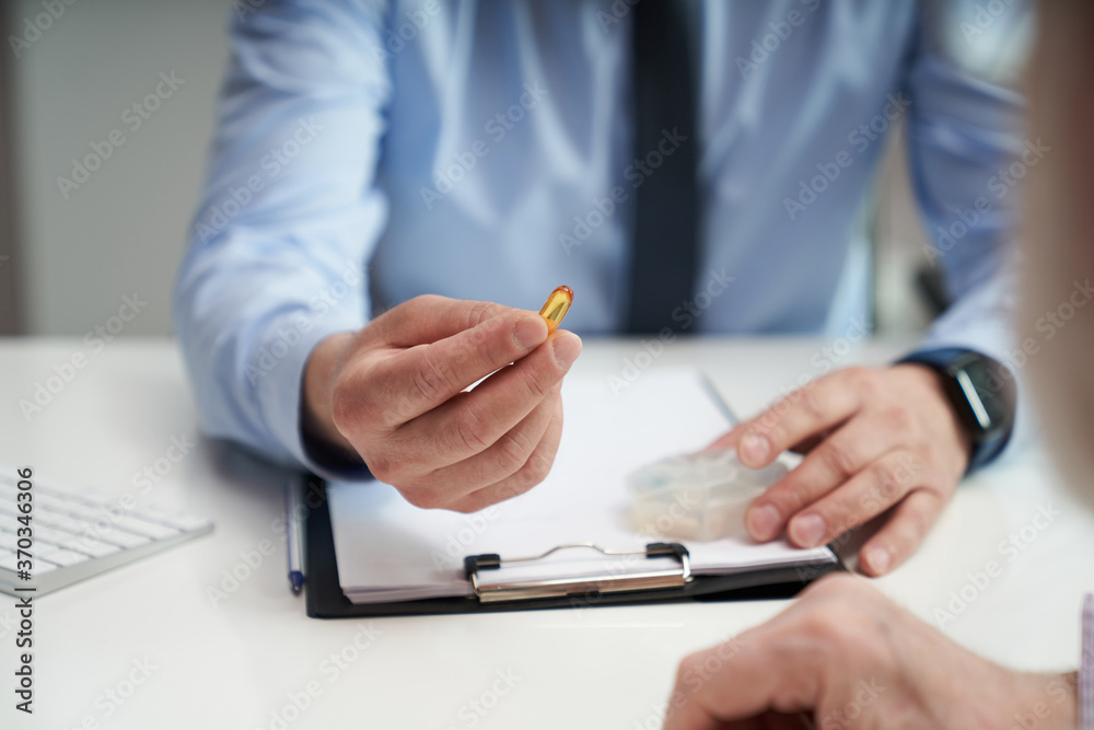 Medical specialist taking a yellow pill out of pill organizer Medical specialist taking a yellow pill out of pill organizer