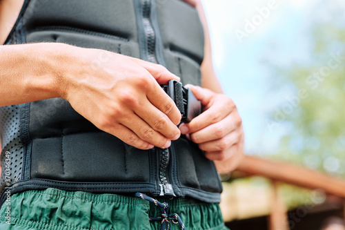 Foto Hands of young sportsman fastening safety belt on waist of black sports jacket