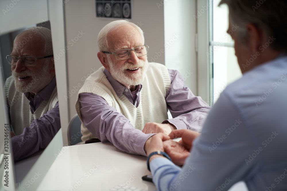 Fototapeta premium Senior citizen having his wrist checked by a healthcare worker