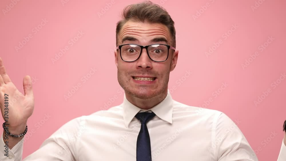 elegant young businessman in white shirt making faces, pointing fingers to temples and grimacing on pink background elegant young businessman in white shirt making faces, pointing fingers to temples and grimacing on pink background