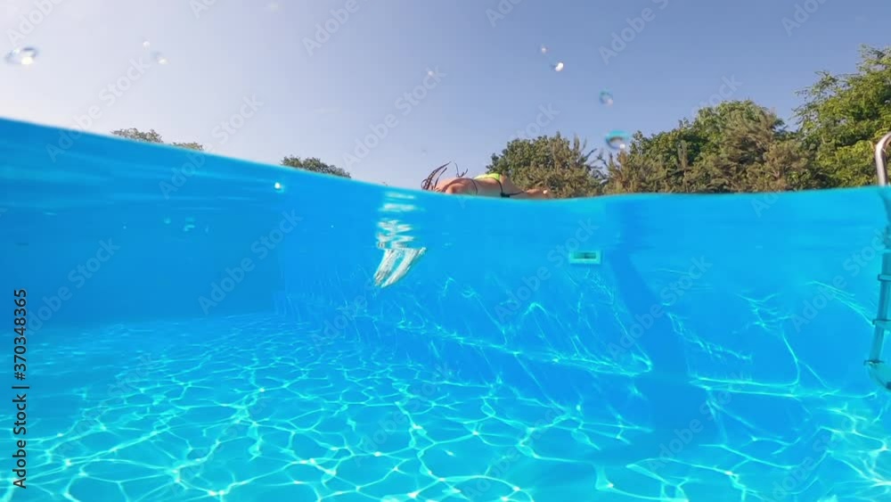 Underwater shooting. Girl dive in blue swimming pool.