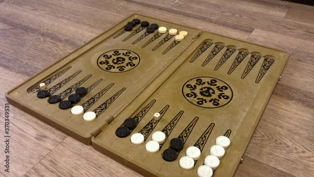Detail of a backgammon game with two dice close up. Male hands rolling two dice and moving checkers on board. Young people playing backgammon while relaxing. 4k. Detail of a backgammon game with two dice close up. Male hands rolling two dice and moving checkers on board. Young people playing backgammon while relaxing. 4k.