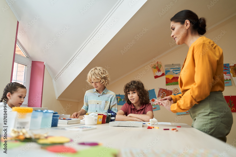 Cheerful kids enjoying art lesson with teacher