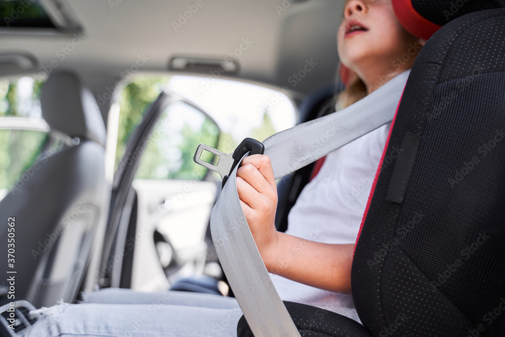 Little girl using safety belt in automobile chair