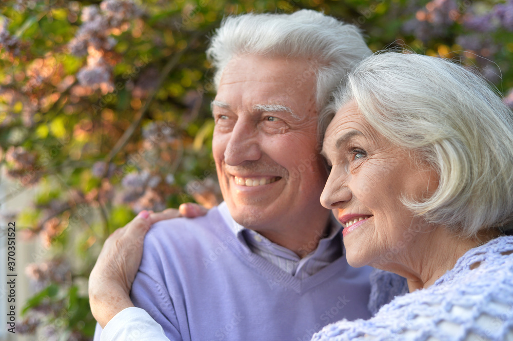 Portrait of beautiful senior couple hugging in the park by lilacs Portrait of beautiful senior couple hugging in the park by lilacs