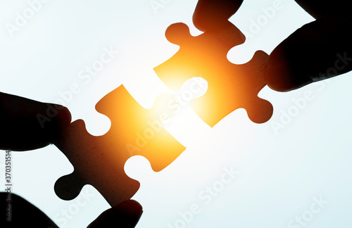 Closeup of hand holding and connect jigsaw puzzle with sunlight. Business corporate solution problem concept.