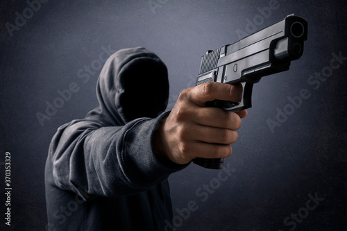 Fototapet Hooded man with a gun in the dark