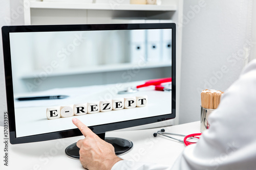 Doctor in the practice touching monitor, word e-rezept on dices, german elektronisches rezept photo
