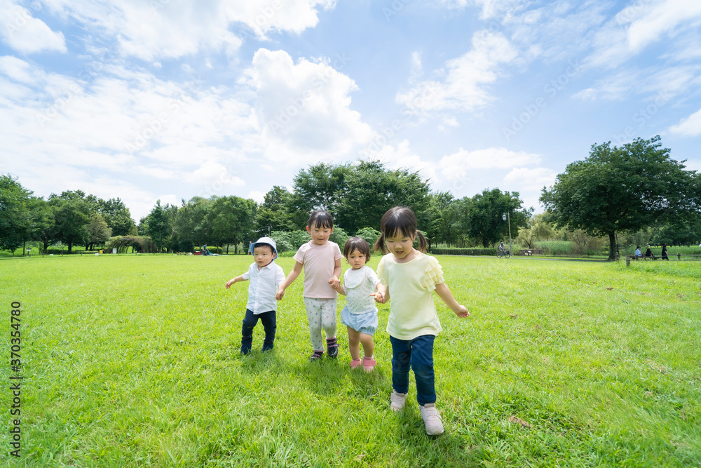 Obraz premium 青空の下、手を繋いで元気に歩く子供たち