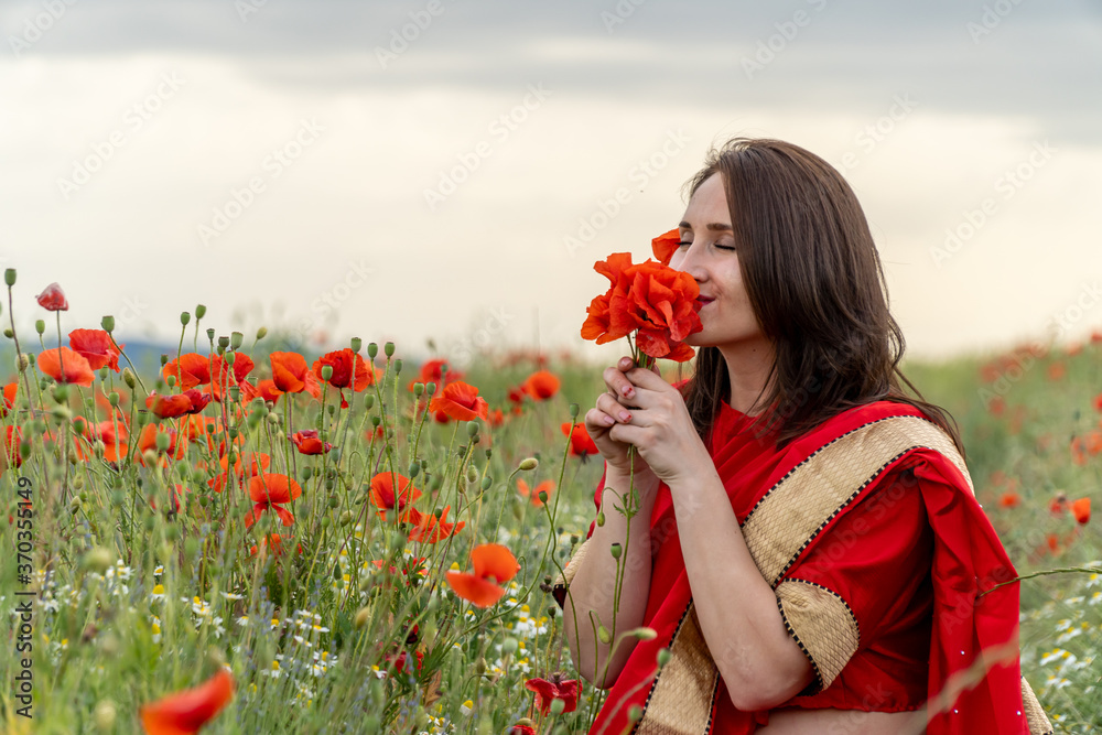 Yound girl dressed in Indian Sari in a poppy flower garden Yound girl dressed in Indian Sari in a poppy flower garden