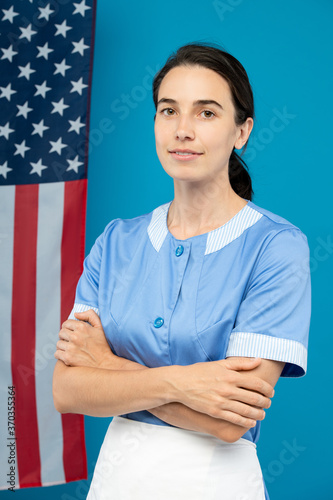 Young confident chambermaid in blue uniform crossing her arms by chest