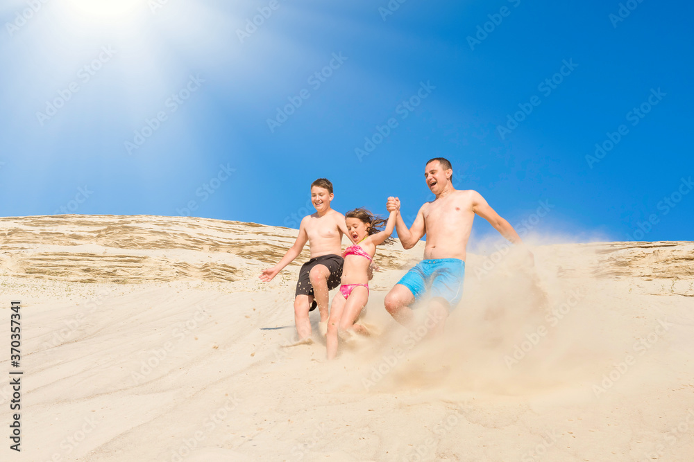 Happy family have fun running along the sand on the beach on a sunny summer day. Family vacation. Healthy lifestyle.