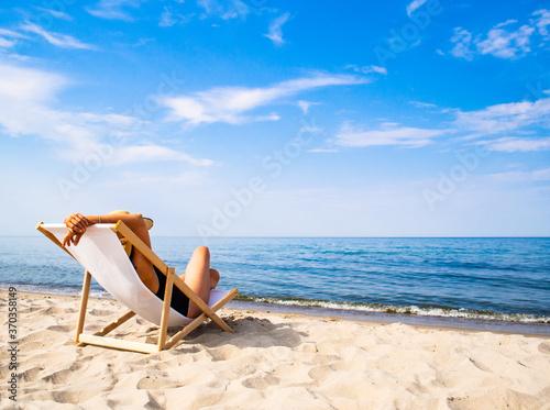 Canvas-taulu Woman relaxing on beach sitting on sunbed