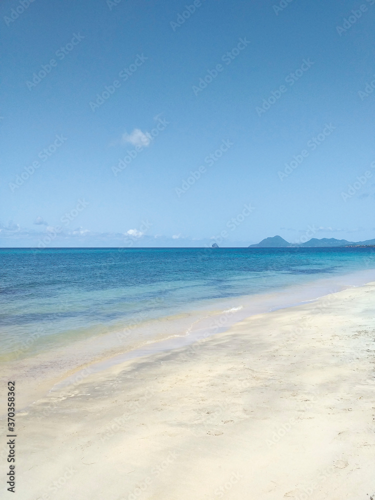 Turquoise waters of the Caribbean Sea and fine white sand under tropical blue skies. Exotic tropical paradise beach and idyllic landscape background. Tropical sandy beach of the Caribbean island.