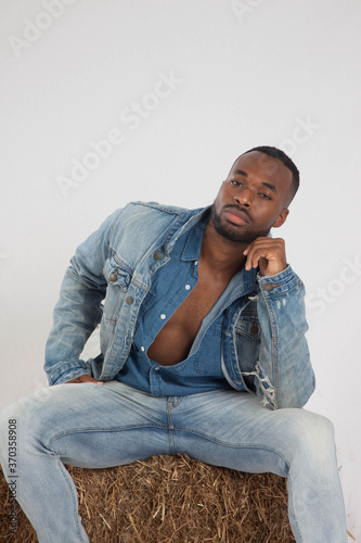 Thoughtful black man sitting on a bale of hay © Allen Penton