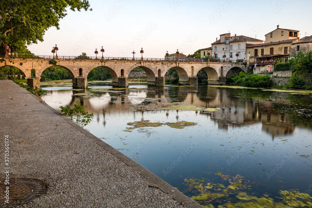 Vue au coucher du soleil sur le Pont Tibère et sa réflexion sur les eaux du fleuve Vidourle à Sommières (Occitanie, France)