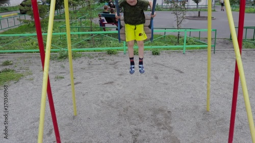 Little boy swinging on a swing. Summer, boy rejoices, front view, video