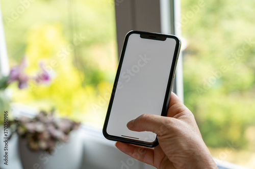 Woman hand holding the black smartphone with blank screen and modern frameless design Frau hält Smartphone in der Hand