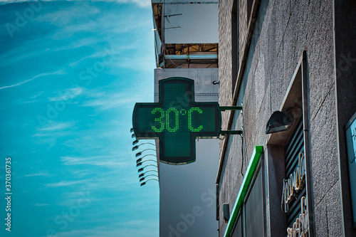 30 degrees celsius, 86 fahrenheit is the temperature displayed by a digital thermometer on a hot summer outside a pharmacy in Milan