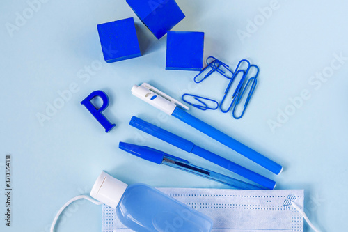 Education or back to school concept. Blue school supplies and medical face mask. New normal during coronavirus pandemic. Virus protection, keep distance. Copy space for text