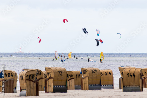 A big crowd of wind and kite surfers at the Baltic Sea near Laboe in Germany with wicker beach chairs in the foreground