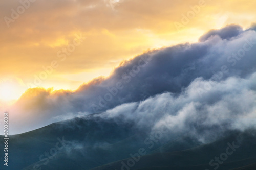 Beautiful sunset landscape. Close-up mountains view in the huge clouds on the sunset.