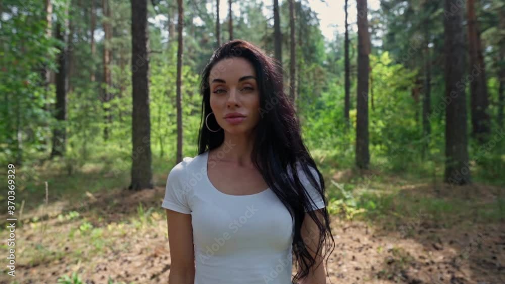 Woman standing in a sunny clearing near a forest Woman standing in a sunny clearing near a forest