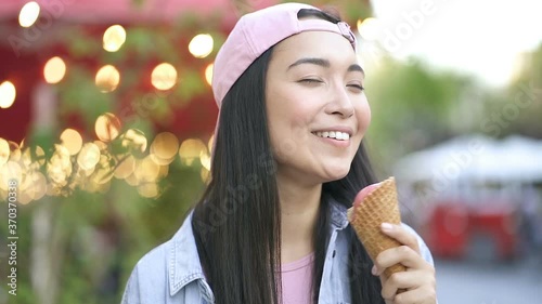 Close up portrait of asian woman licking icecream and smiling. Slowmotion. photo