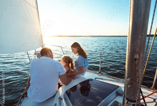 Family Of Three Sitting On Yacht Deck Sailing In Sea © Prostock-studio