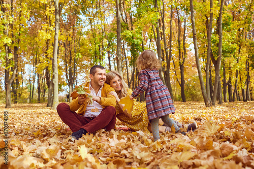 Family playing with a baby in the park in autumn.