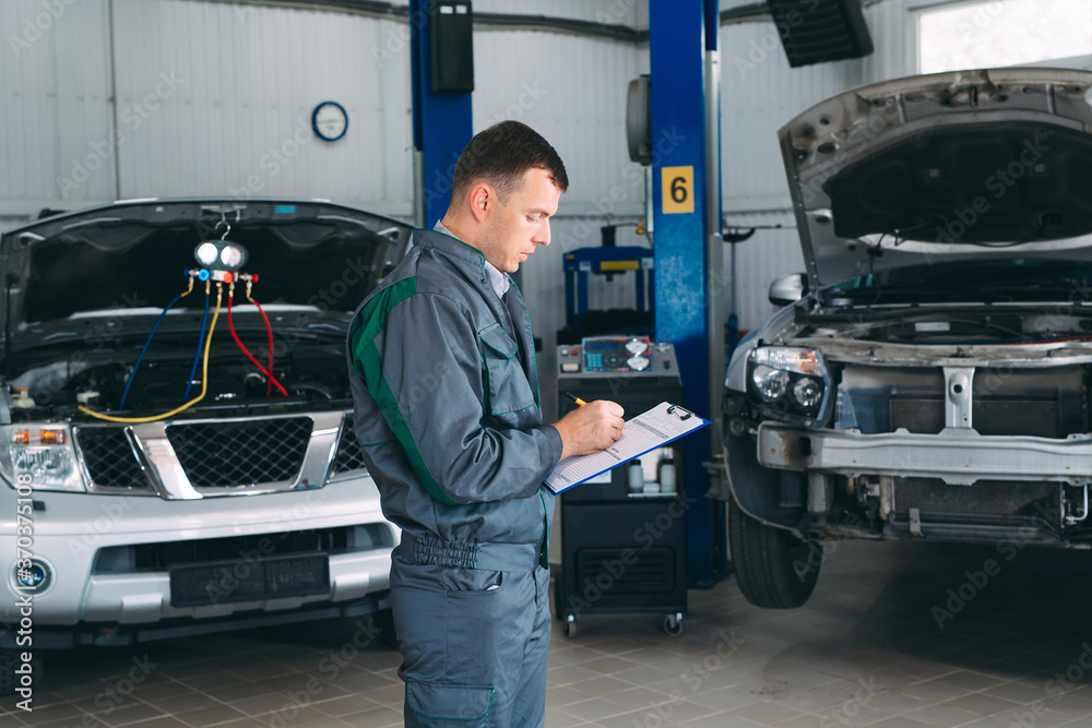 mechanic maintaining car record on clipboard at the repair shop.