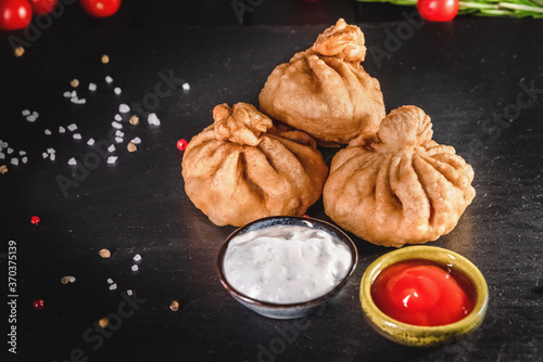 Appetizing traditional fried dumplings on a dark background among spices and sauces. Traditional food concept photo