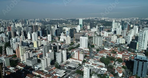 Lateral movement to the left filmed with Drone in large metropolis, city full of buildings, soft evening light, mobility, traffic, confidence, in 4K resolution photo