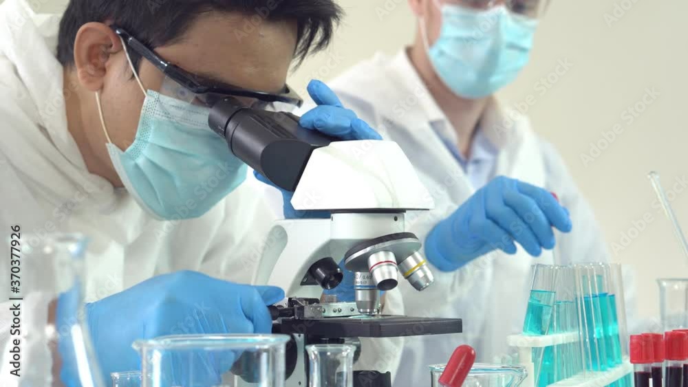 asian scientist and caucasian assistant doing experiment on new drug and vaccine in lab. science concept asian scientist and caucasian assistant doing experiment on new drug and vaccine in lab. science concept