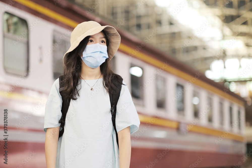 Obraz premium Asian travelers girl take a picture in train station with medical face mask to protection the Covid-19, new normal lifestyle