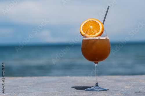 A glass of ice orange juice and sea and blue sky