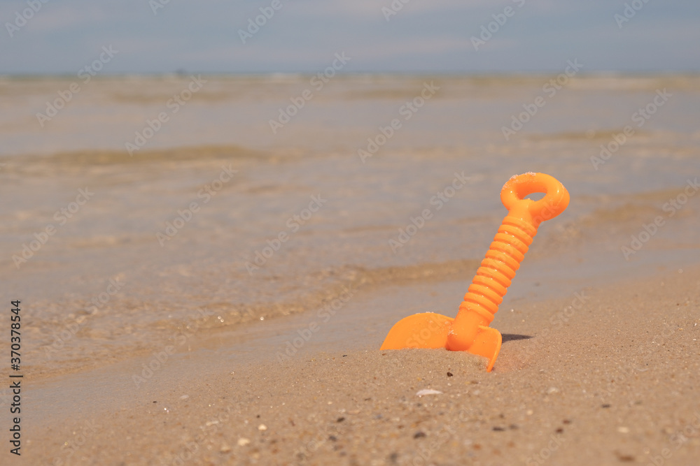 Naklejka premium Orange plastic toy on the beach