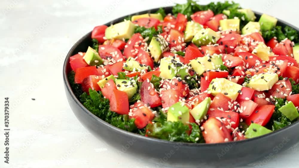 Kale salad with tomatoes and avocado in black plate. Healthy raw vegan lunch concept. Kale salad with tomatoes and avocado in black plate. Healthy raw vegan lunch concept.