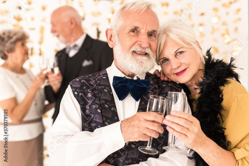 Cute elegant senior couple toasting with champagne during New Year's Eve