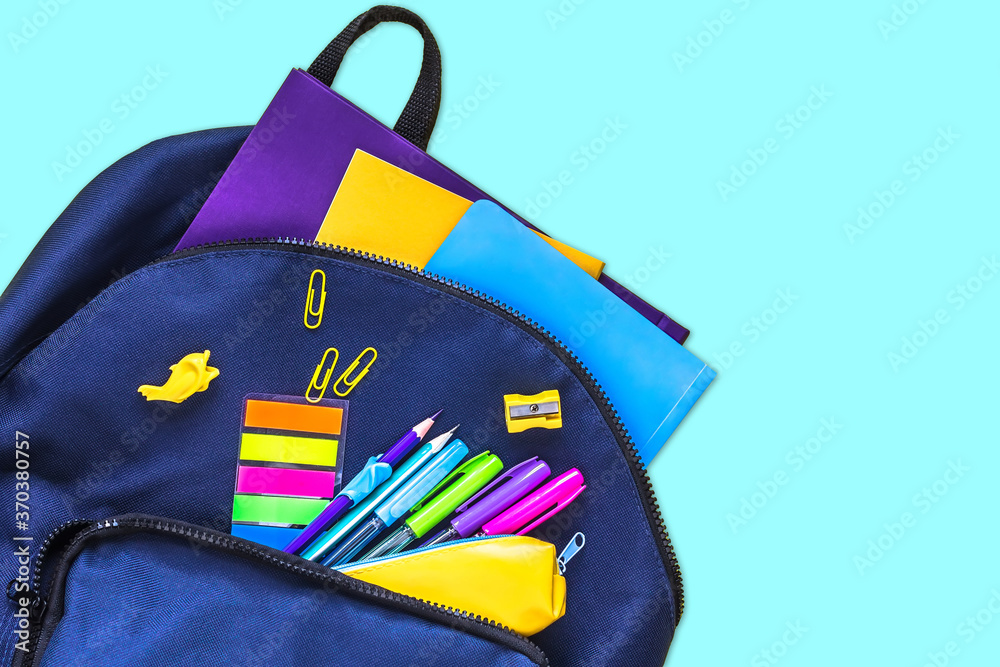 Naklejka premium The concept of going back to school. Blue school bag with school supplies on a blue background. Space for text. The view from the top