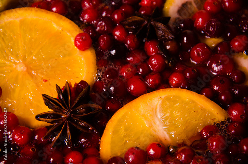 metal pot on the stove. Oranges and cranberries in mulled wine