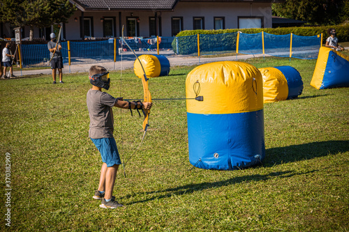 Teenage boy playing archery tag on a meadow