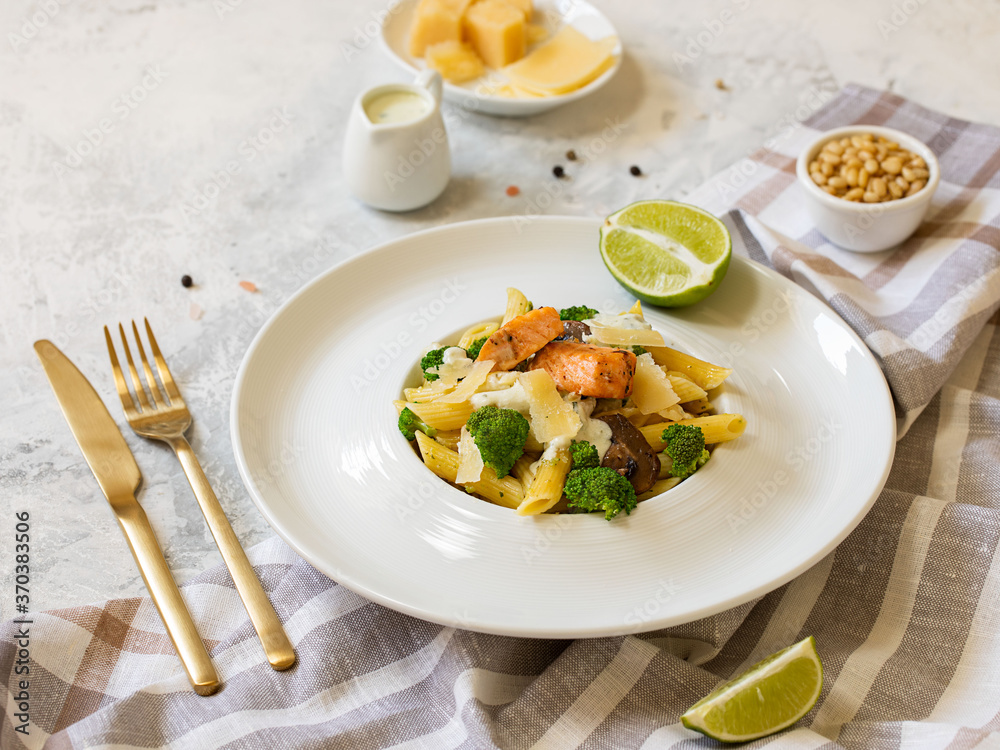 Pasta penne with salmon, broccoli, and pesto sauce on the white-gray background. Flat lay. Pasta penne with salmon, broccoli, and pesto sauce on the white-gray background. Flat lay.