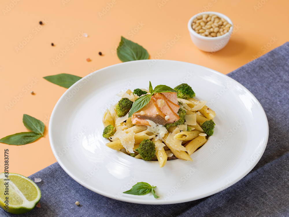 Pasta penne with salmon, broccoli, and pesto sauce on the pink-yellow background. Flat lay. Pasta penne with salmon, broccoli, and pesto sauce on the pink-yellow background. Flat lay.