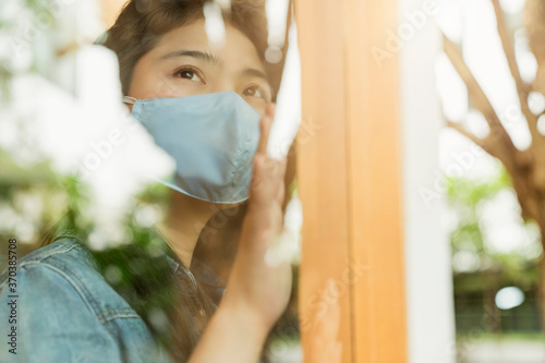 asian female casual shirt wear facial mask virus protection new normal lifestyle sit relax next to window glass with reflect of garden outside health and ideas concept