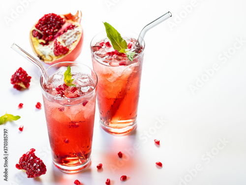 Pomegranate juice on a white background in glass glasses with glass straws.