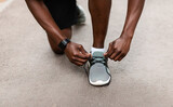 African sportsman fixing his sneakers during exercising outdoors