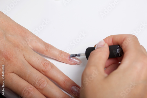 A woman gives herself a manicure. Apply new nail Polish with a brush. Taken in close-up.